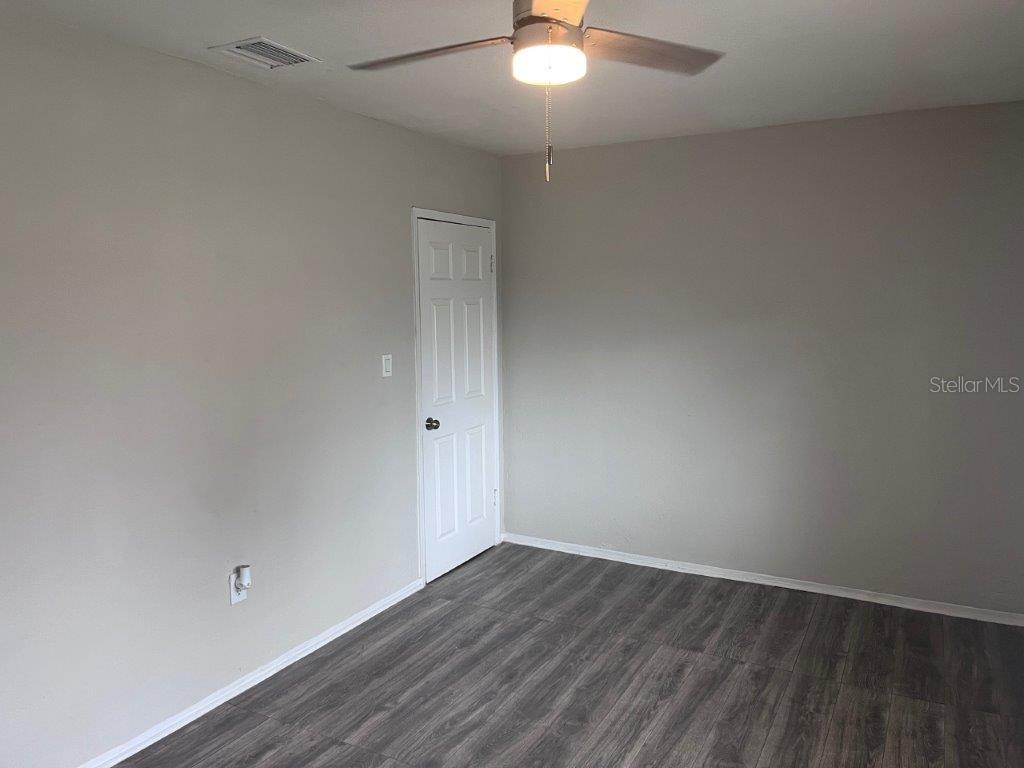An empty room features light gray walls, dark wood-look flooring, and a ceiling fan — 1040 AVONDALE AVENUE, ORLANDO, FL