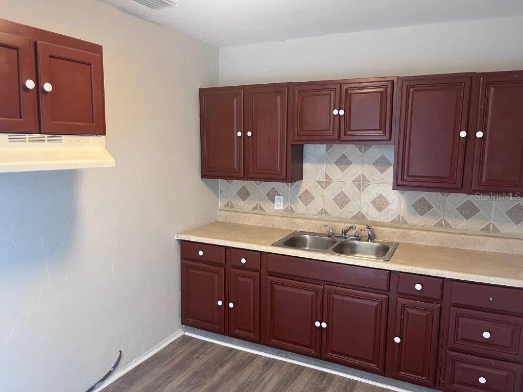 A kitchen features dark wood cabinets, a light countertop, and a tiled backsplash — 1040 AVONDALE AVENUE, ORLANDO, FL