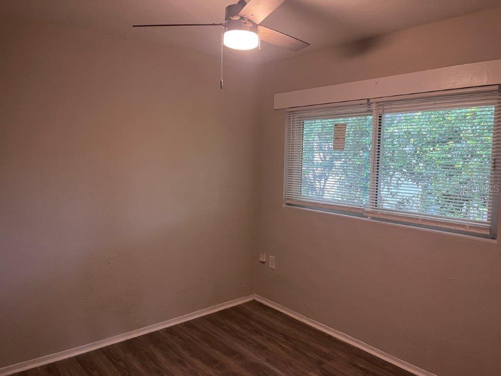An empty bedroom features light-colored walls, wood-look flooring, a ceiling fan, and a window — 1040 AVONDALE AVENUE, ORLANDO, FL