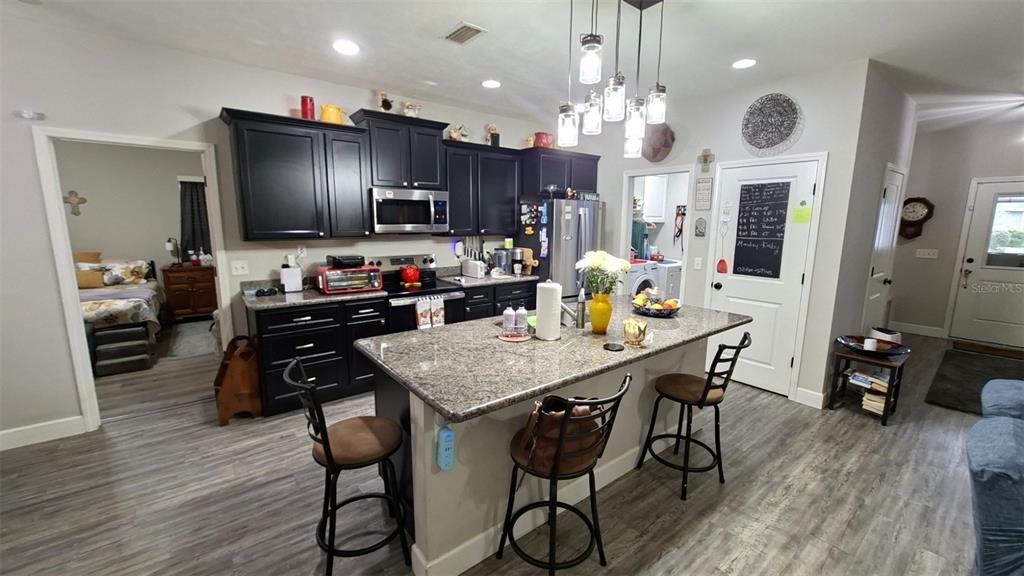 A kitchen features dark cabinets, a granite-topped island with bar seating, and light flooring — 20074 NW 249TH STREET, HIGH SPRINGS, FL