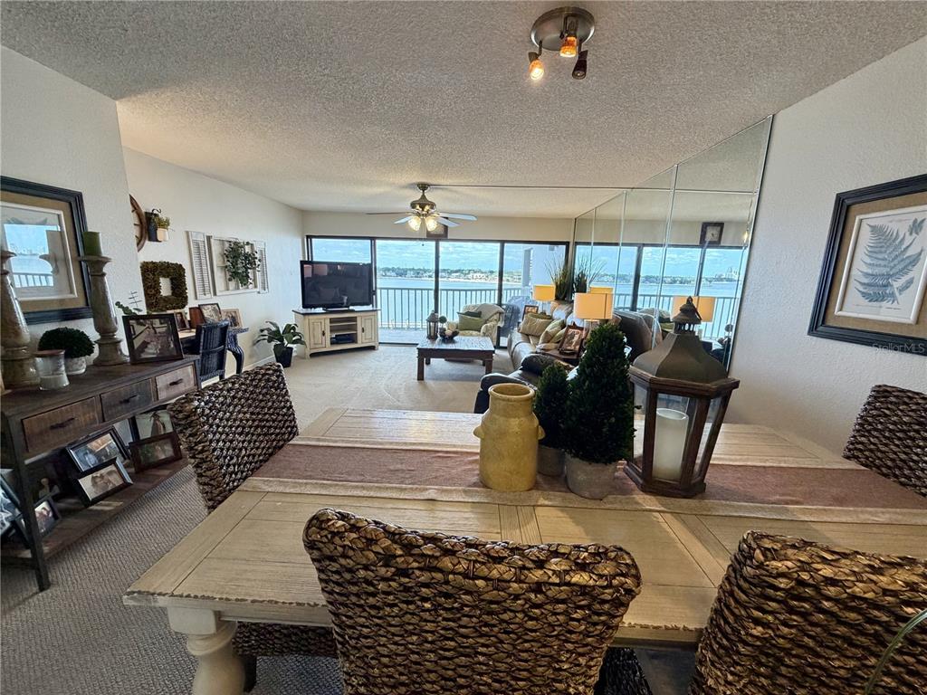A dining area with woven chairs overlooks a living room with a waterfront balcony view — 2 ADALIA AVENUE UNIT 405, TAMPA, FL