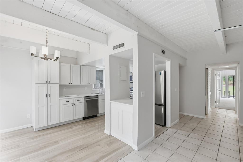 A bright kitchen features white cabinets, stainless steel appliances, and wood-look flooring — 100 FAIRWAY DRIVE UNIT 100, LONGWOOD, FL