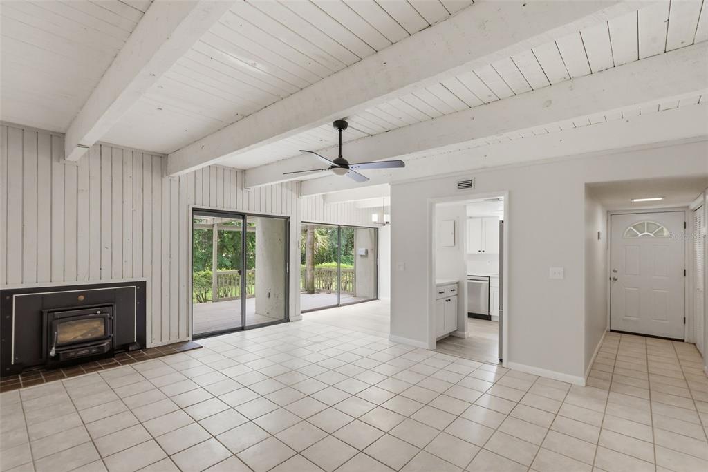 A living room features white tile floors, a wood-burning stove, and exposed ceiling beams — 100 FAIRWAY DRIVE UNIT 100, LONGWOOD, FL