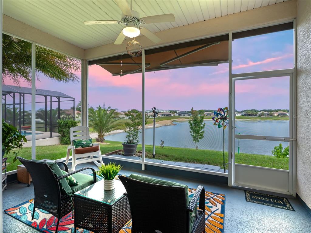 A screened-in patio features outdoor furniture, a ceiling fan, and a view of a lake — 11227 SE 172ND PLACE, SUMMERFIELD, FL
