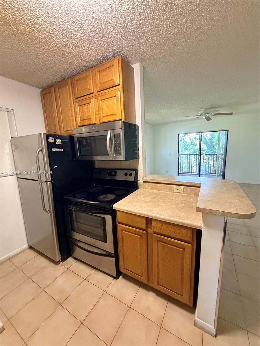 This kitchen features wood cabinets, stainless steel appliances, and a breakfast bar counter — 588 Trace Cir # 202, Deerfield Beach FL 33441, DEERFIELD BEACH, FL