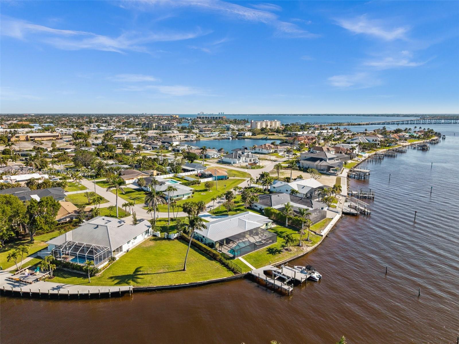 An aerial view shows waterfront homes with private docks and swimming pools along a canal — 1600 Edith Esplanade, Cape Coral FL 33904, CAPE CORAL, FL