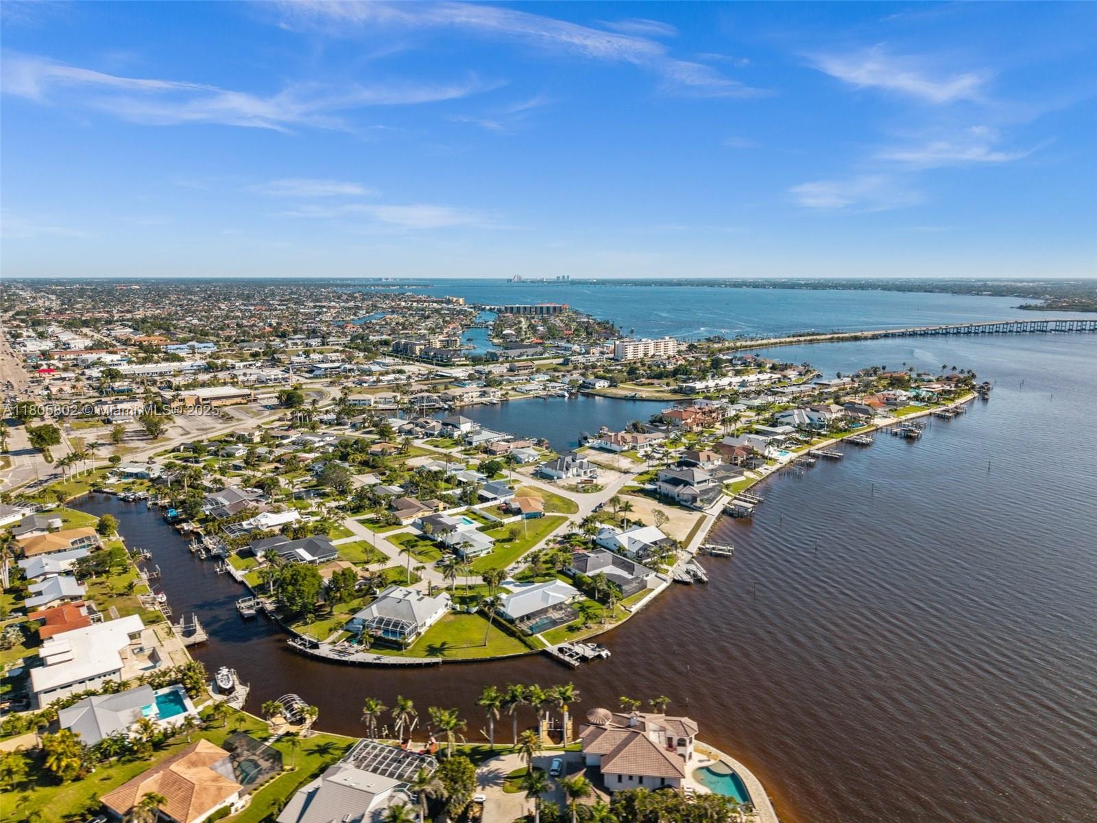 An aerial view shows waterfront homes with private docks along a canal and bay — 1600 Edith Esplanade, Cape Coral FL 33904, CAPE CORAL, FL