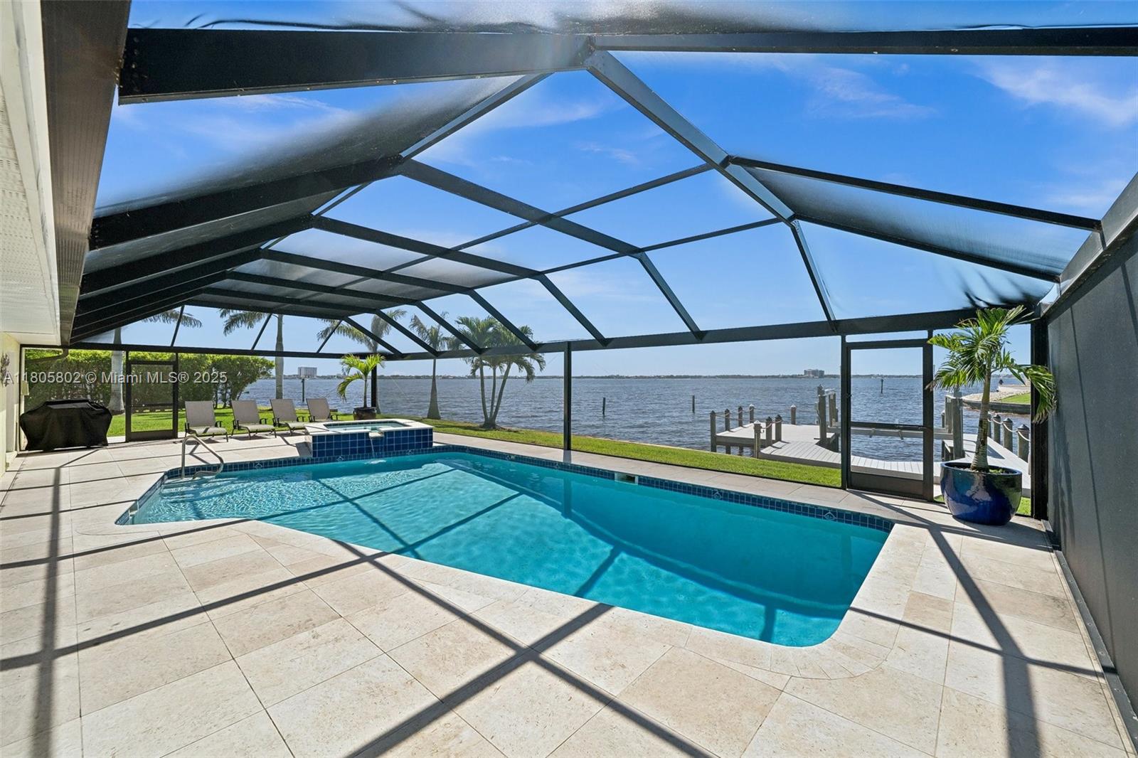 A screened-in pool and hot tub overlook a body of water with a private dock — 1600 Edith Esplanade, Cape Coral FL 33904, CAPE CORAL, FL
