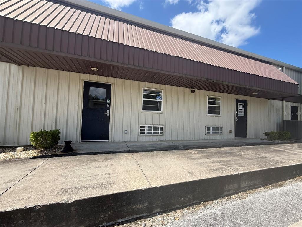 The exterior of a commercial building features two dark doors, windows, and a metal awning — 4344 SE 95TH STREET UNIT 2, OCALA, FL