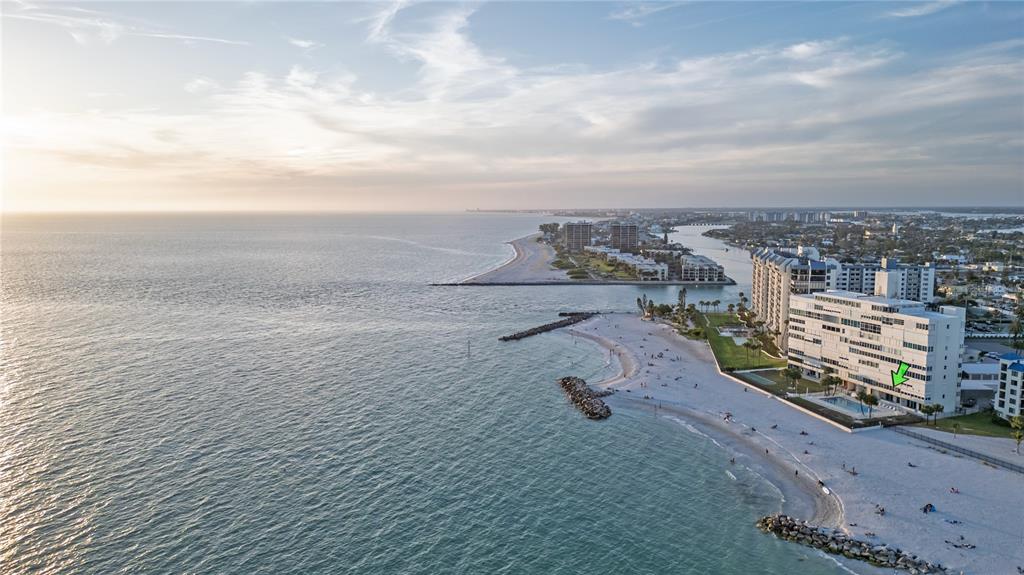 An aerial view shows a beachfront condominium building with a green arrow pointing to a unit — 7000 BEACH PLAZA UNIT 202, ST PETE BEACH, FL