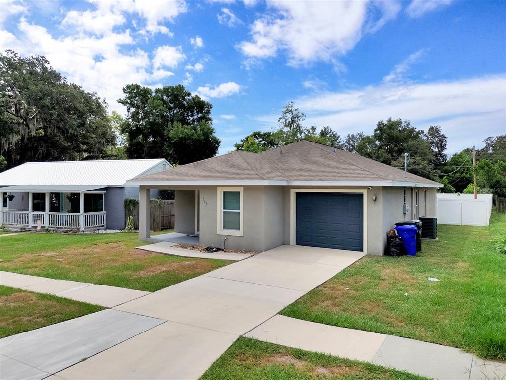 A gray single-story house with a dark blue garage door and a concrete driveway — 1509 E ELM ROAD, LAKELAND, FL