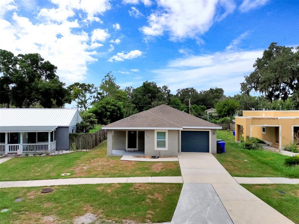 A single-story house with a gray stucco exterior, blue front door, and attached garage — 1509 E ELM ROAD, LAKELAND, FL