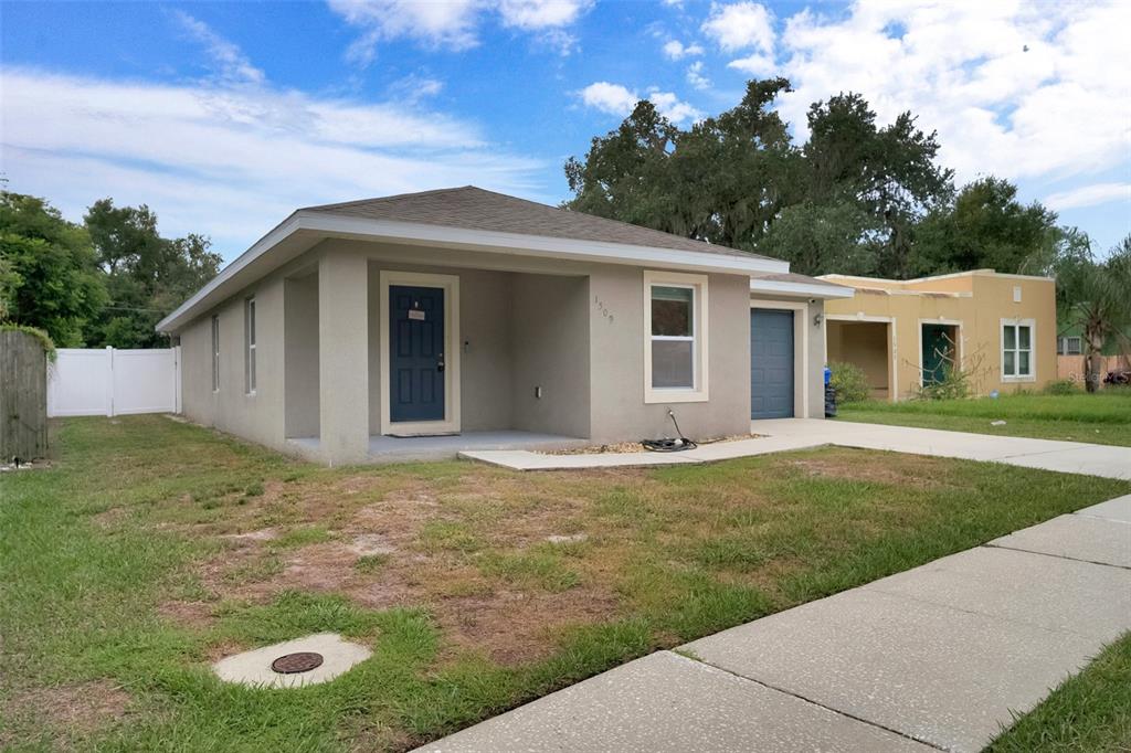 A bright, open-concept living area features white walls, light tile flooring, and a vaulted ceiling — 1509 E ELM ROAD, LAKELAND, FL