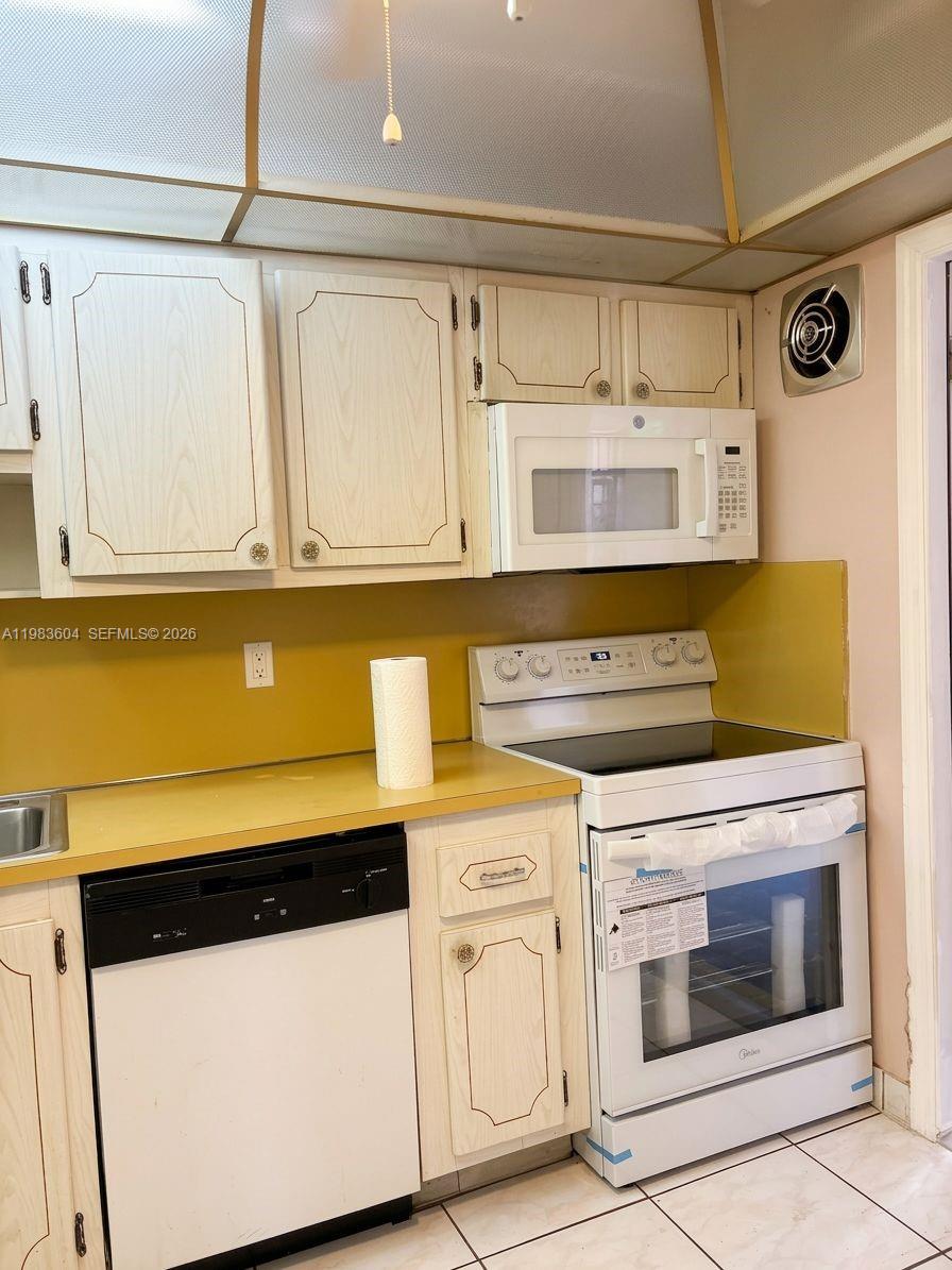 A kitchen features white cabinets, yellow countertops, a white stove, and a white dishwasher — 410 SE 2nd St # 102, Hallandale Beach FL 33009, HALLANDALE BEACH, FL