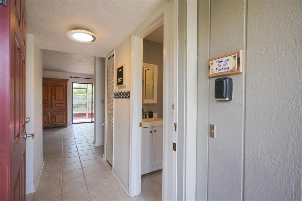 An entryway leads to a tiled hallway with a bathroom and a view of a patio — 3150 WET N WILD COURT, KISSIMMEE, FL