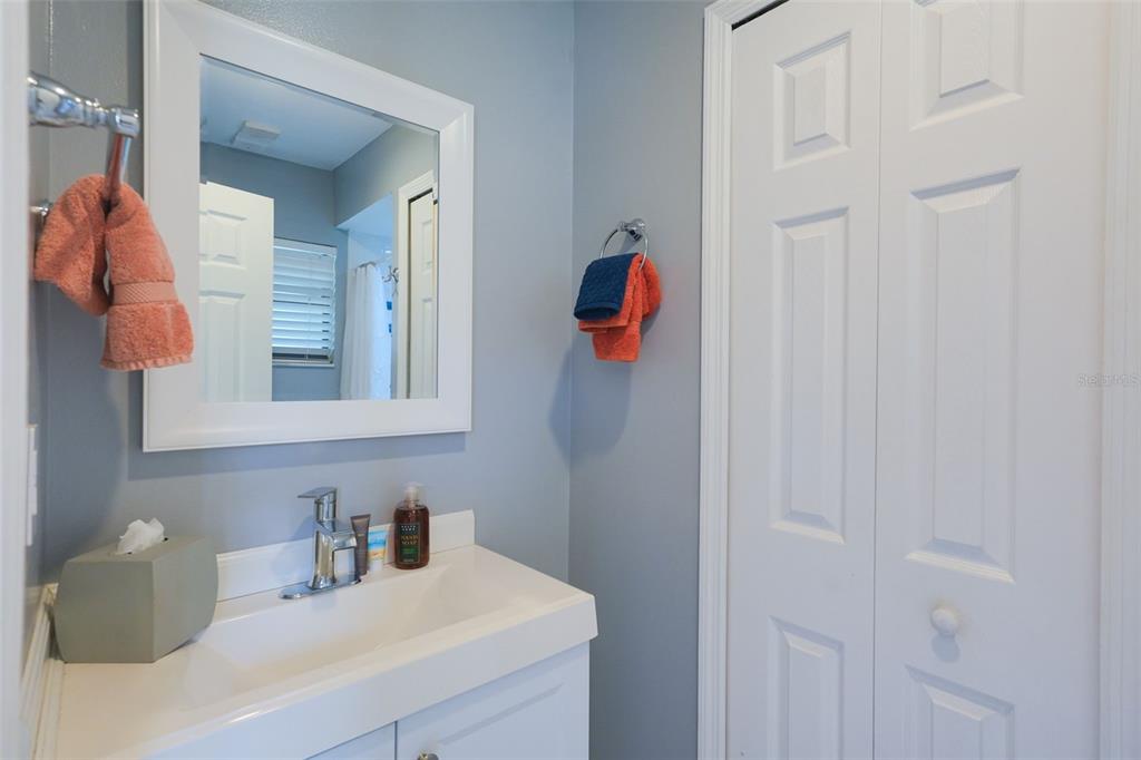 A bathroom features a white vanity, a mirror, blue walls, and a white bifold door — 3150 WET N WILD COURT, KISSIMMEE, FL