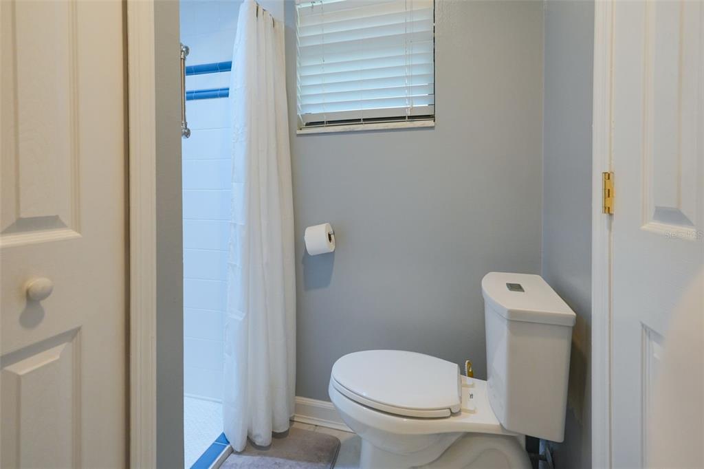 A bathroom features a white toilet, a shower with a white curtain, and gray walls — 3150 WET N WILD COURT, KISSIMMEE, FL
