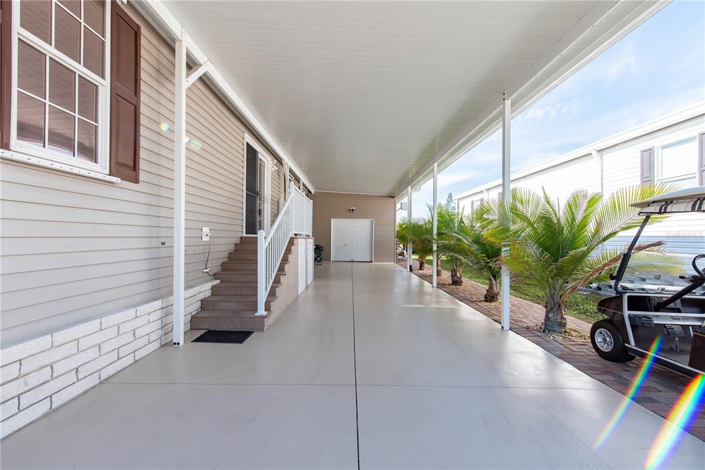 A covered carport with a concrete floor leads to a set of stairs and a door — 1 DEN HELDER AVENUE, PUNTA GORDA, FL