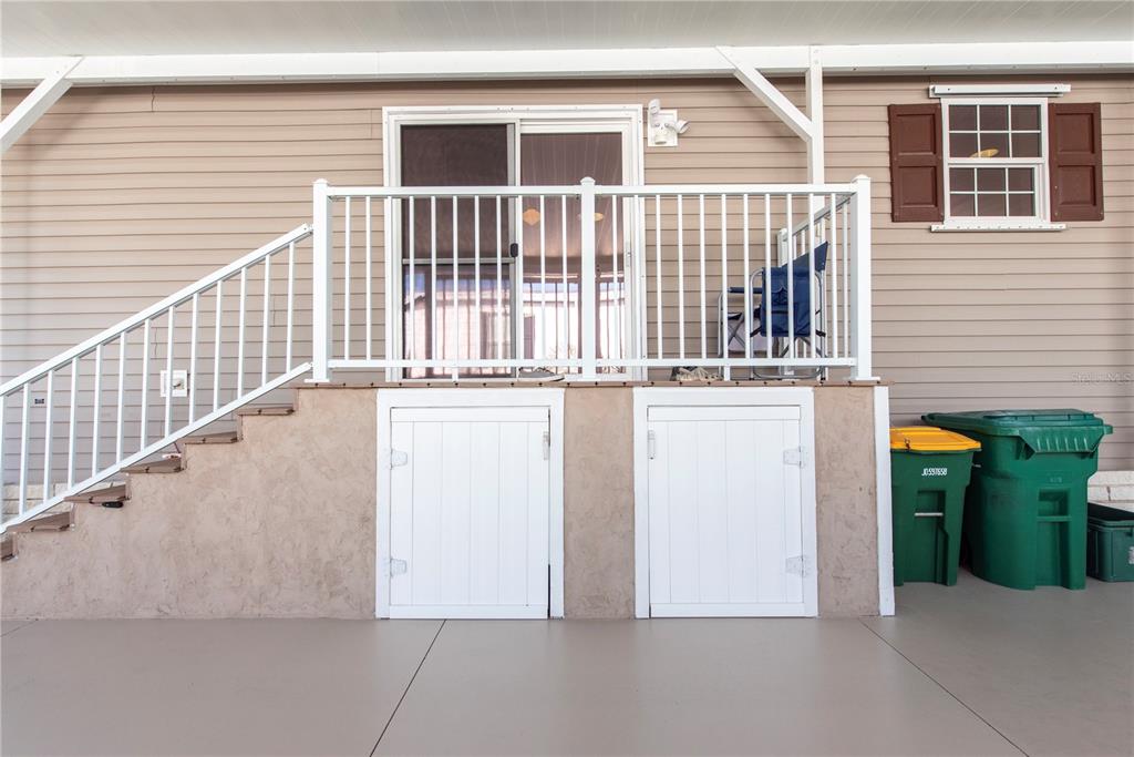 An exterior view of a home with a raised deck, stairs, and storage access doors — 1 DEN HELDER AVENUE, PUNTA GORDA, FL