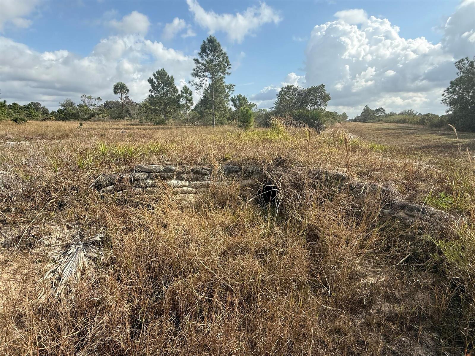 A low, stacked stone wall structure sits in a field of tall, dry grass — 16375 NW 314th Street, Okeechobee FL 34972, OKEECHOBEE, FL