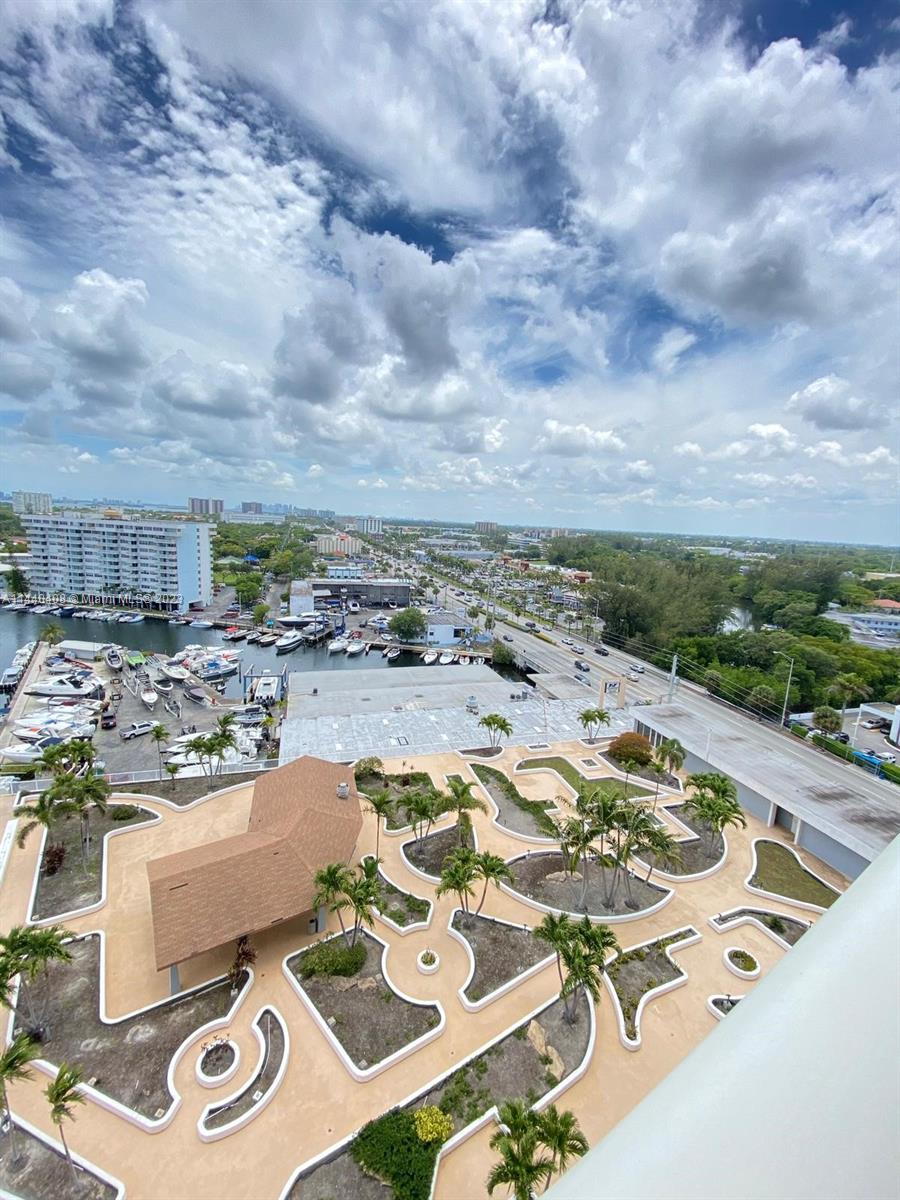 An elevated view of a landscaped pool deck, a marina with boats, and a coastal city — 13499 Biscayne Blvd # 1408, North Miami FL 33181, NORTH MIAMI, FL