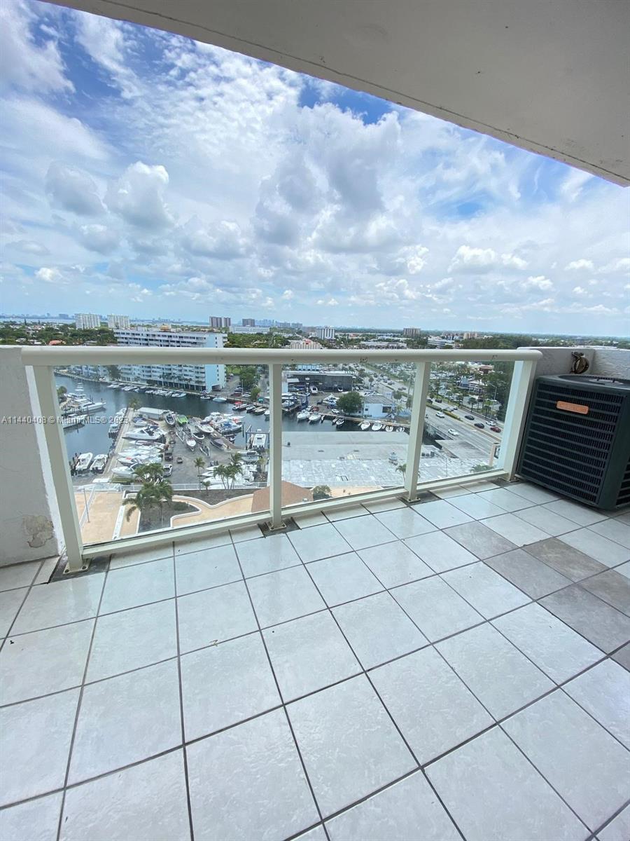 A tiled balcony overlooks a marina and city skyline under a cloudy sky — 13499 Biscayne Blvd # 1408, North Miami FL 33181, NORTH MIAMI, FL