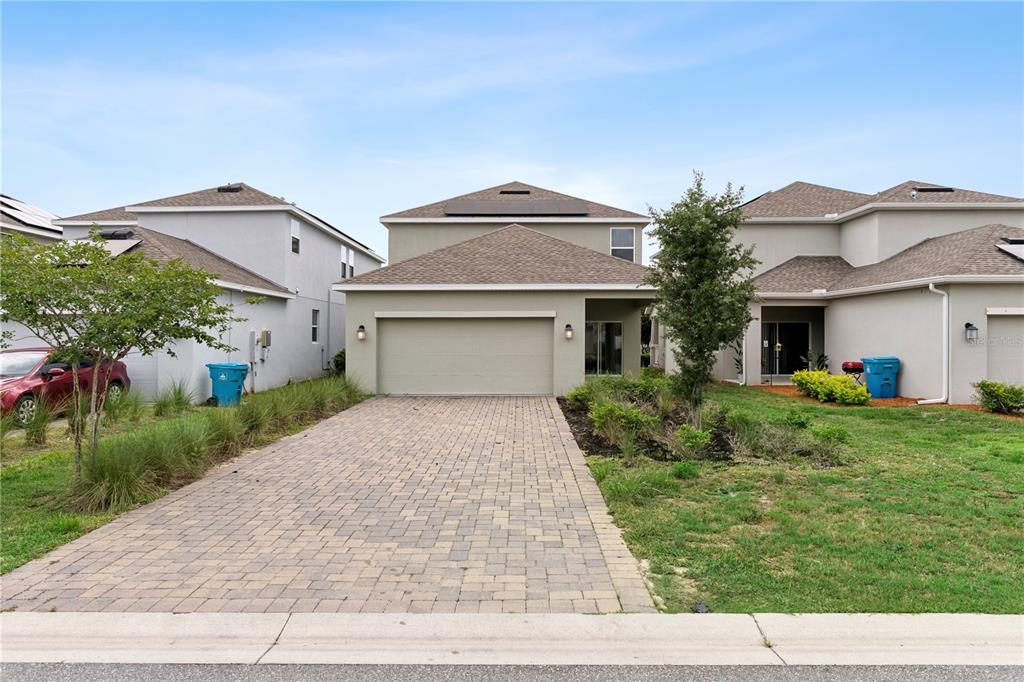 A two-story house with a paved driveway, a two-car garage, and a small front yard — 12018 LANGUAGE WAY, ORLANDO, FL