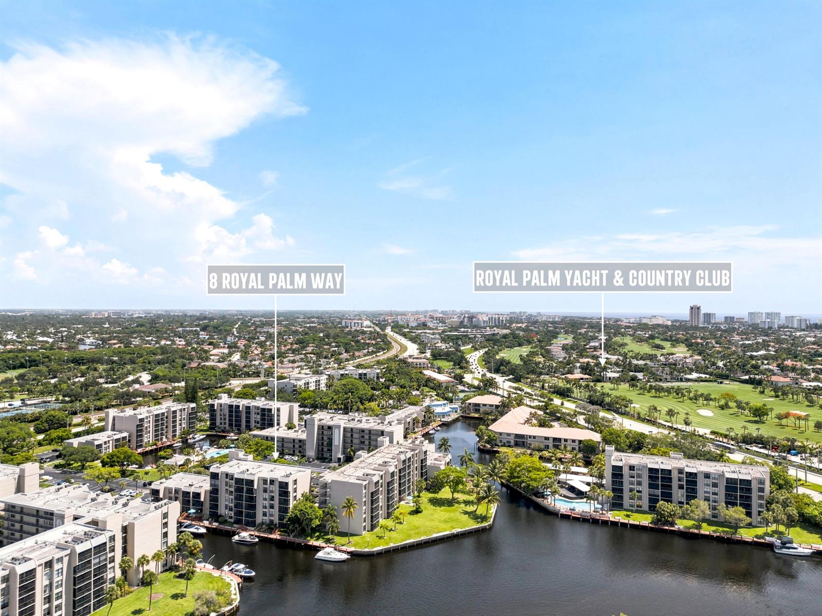 An aerial view shows residential buildings, a canal, and a golf course under a blue sky — 8 Royal Palm Way # 3020, Boca Raton FL 33432, BOCA RATON, FL