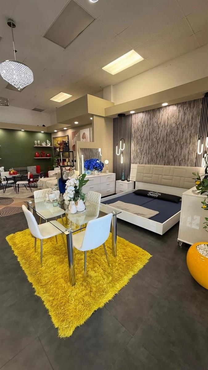 A furniture showroom displays a dining set on a yellow rug near a bed — 5725 NW 7th St, Miami FL 33126, MIAMI, FL