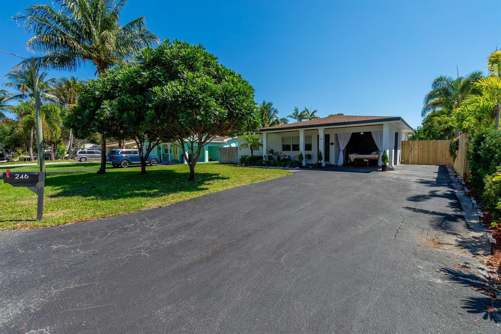 A single-story house with a paved driveway, a covered porch, and surrounding palm trees — 246 NE 14th Street, Delray Beach FL 33444, DELRAY BEACH, FL