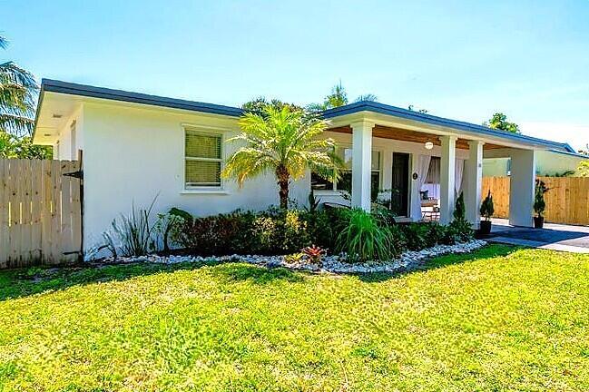 A white single-story house features a covered front porch, a palm tree, and wooden fencing — 246 NE 14th Street, Delray Beach FL 33444, DELRAY BEACH, FL