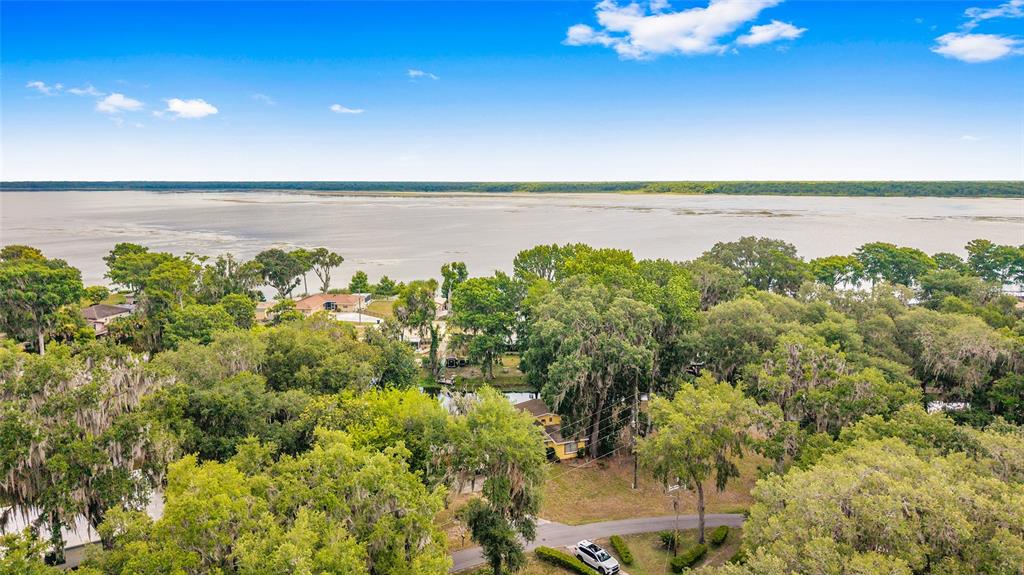 An aerial view shows a house nestled among trees near a large, expansive lake — 2345 CR 453, LAKE PANASOFFKEE, FL