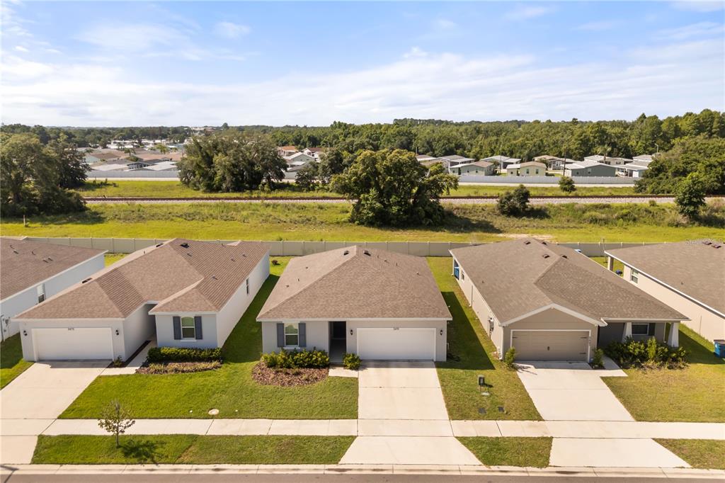 An aerial view shows three suburban single-family homes with driveways and lawns — 5479 MADDIE DRIVE, HAINES CITY, FL