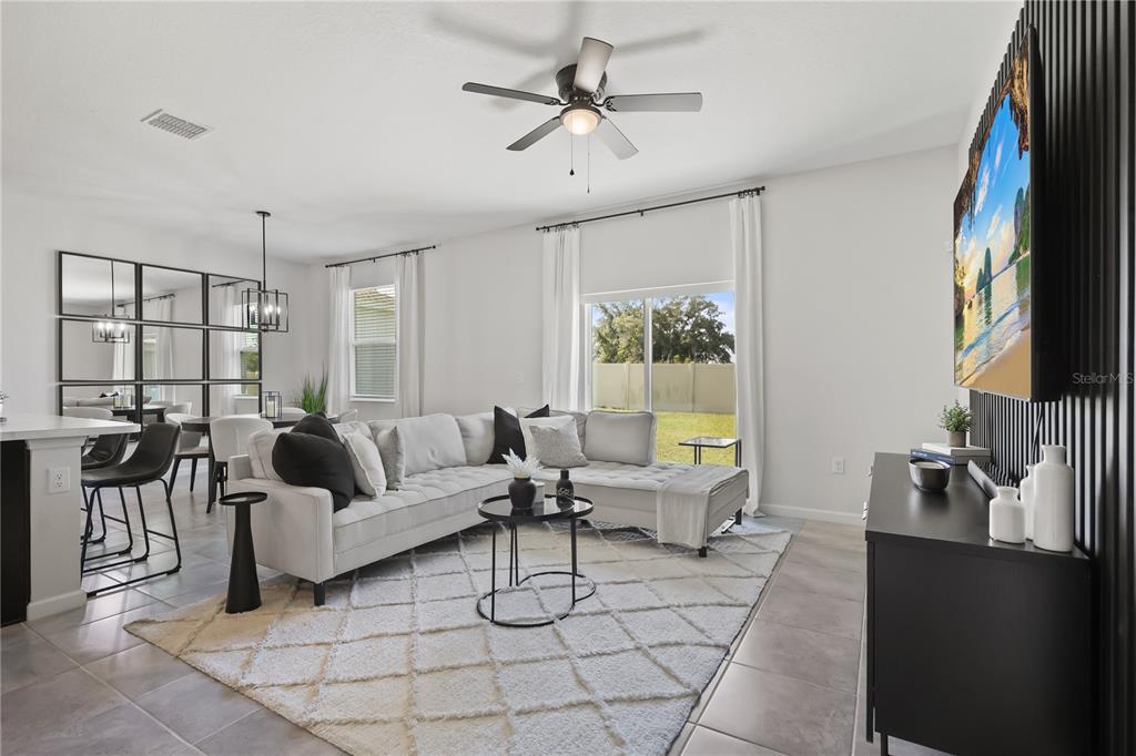 A living room features a sectional sofa, a patterned area rug, and a wall-mounted television — 5479 MADDIE DRIVE, HAINES CITY, FL
