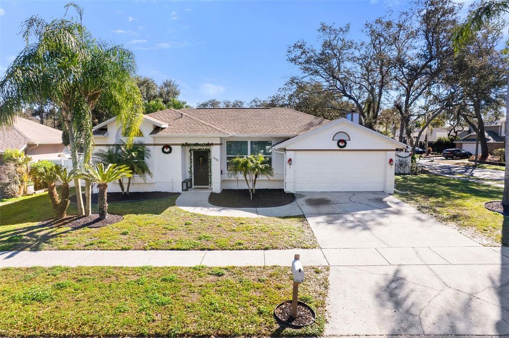 A single-story house with a white stucco exterior, a two-car garage, and a palm-filled yard — 15101 REDVALE DRIVE, TAMPA, FL