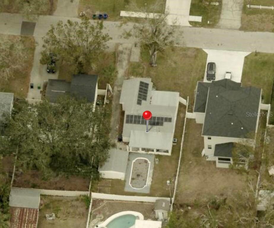 An aerial view shows a house with solar panels on the roof and a backyard pool — 4710 W KNIGHTS AVENUE, TAMPA, FL