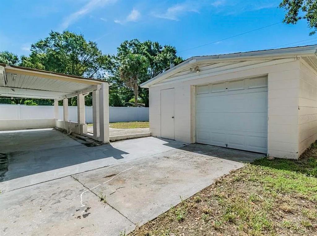 A detached white garage with a side door and an adjacent covered carport — 4710 W KNIGHTS AVENUE, TAMPA, FL
