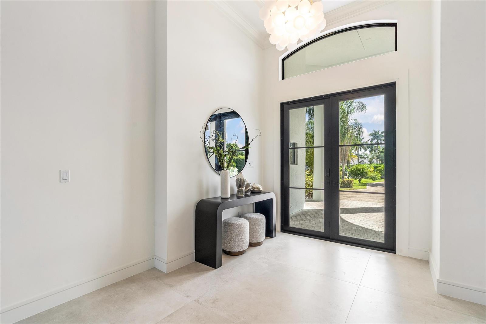 A modern entryway features a black console table, two stools, and glass double doors — 15463 Tall Oak Avenue, Delray Beach FL 33446, DELRAY BEACH, FL