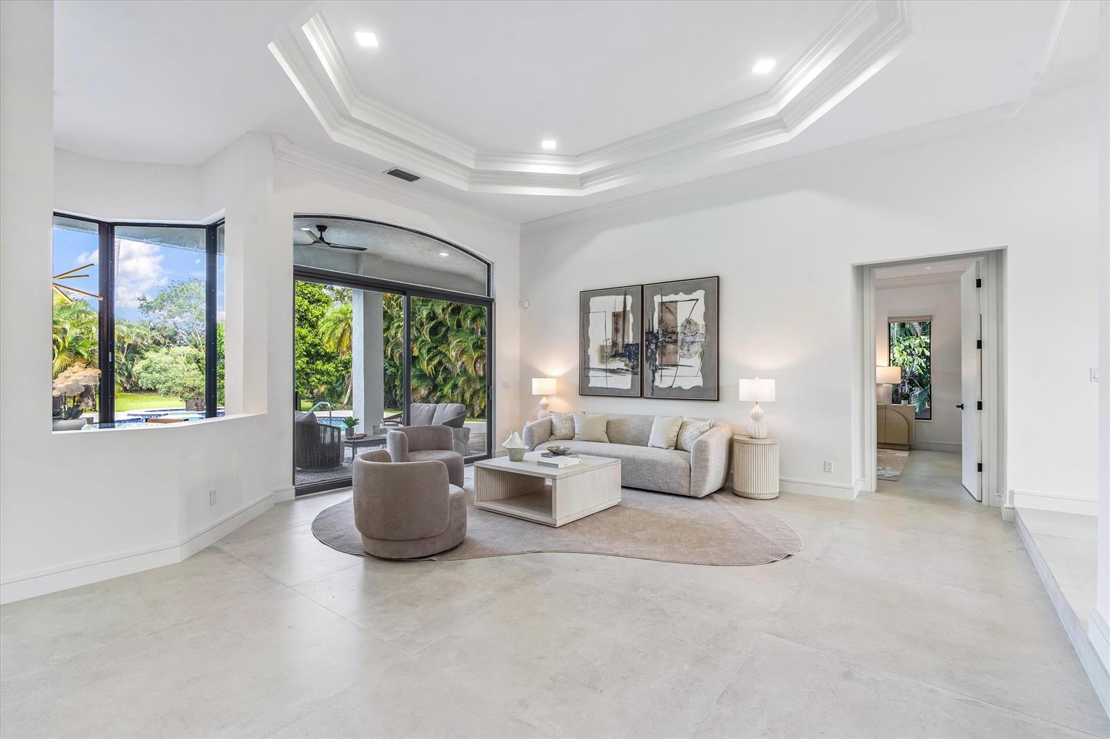 A bright living room features a tray ceiling, large windows, and a neutral furniture arrangement — 15463 Tall Oak Avenue, Delray Beach FL 33446, DELRAY BEACH, FL