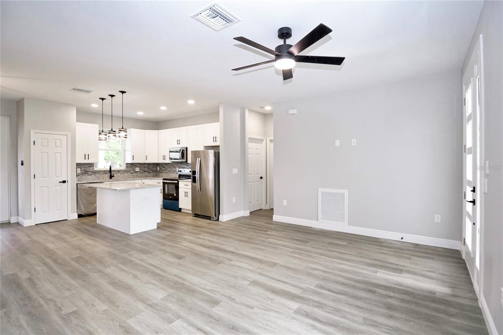 An open-concept kitchen and living area feature white cabinetry, stainless steel appliances, and wood-look flooring — 4510 BOABADILLA AVENUE, SEBRING, FL