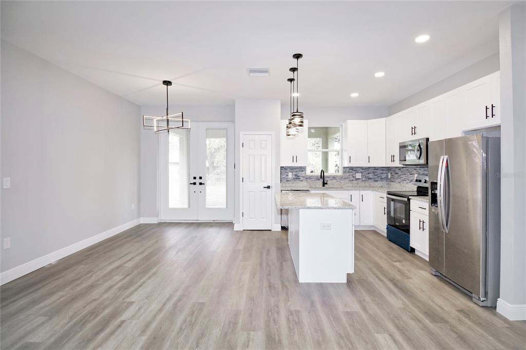 A modern kitchen features white cabinets, granite countertops, stainless steel appliances, and light wood flooring — 4510 BOABADILLA AVENUE, SEBRING, FL