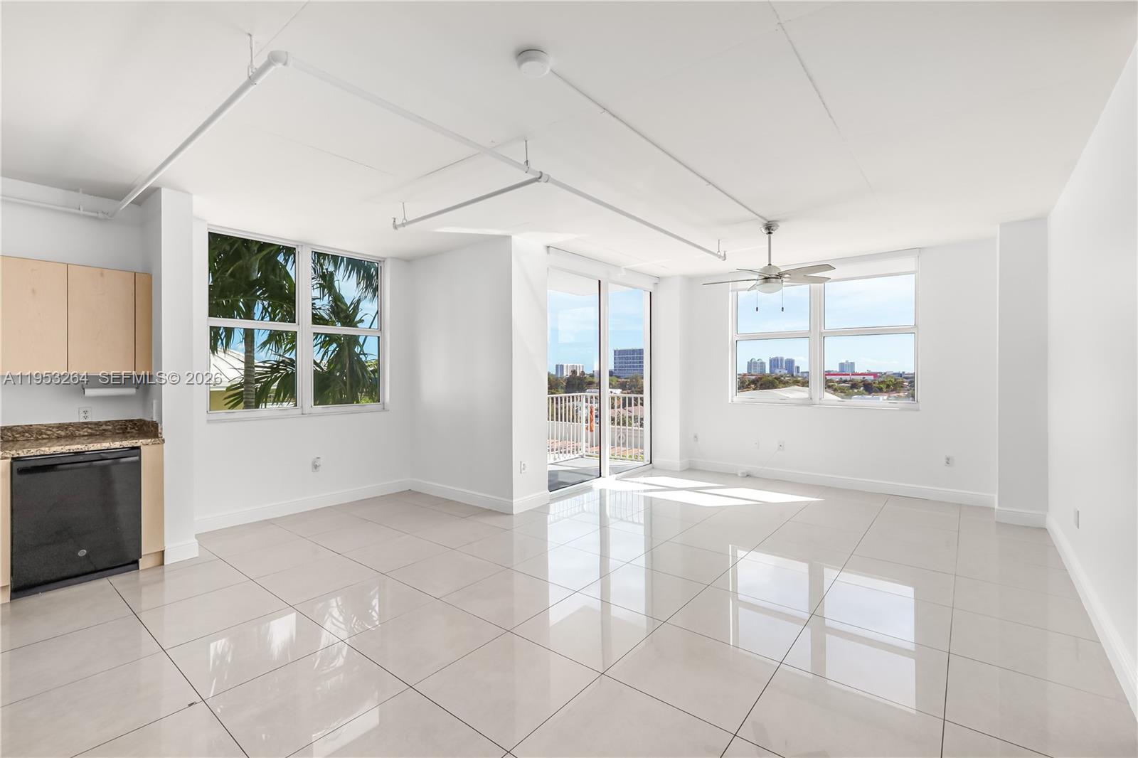An open-concept living area features white tile floors, a kitchen corner, and a balcony door — 3180 SW 22nd st # 601, Miami FL 33145, MIAMI, FL