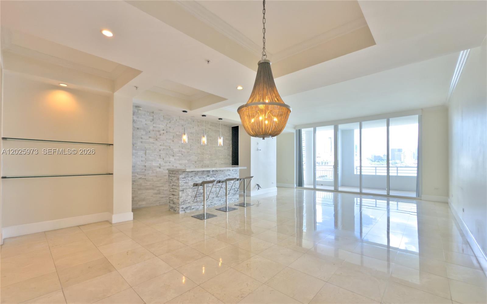 A room features a stone-accented bar, a large chandelier, and floor-to-ceiling windows with balcony access — 848 Brickell Key Dr # 306, Miami FL 33131, MIAMI, FL