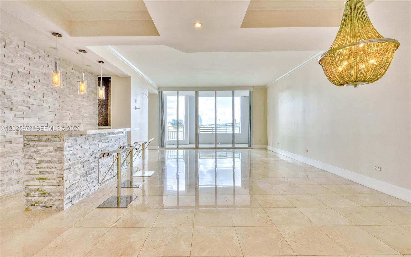 A spacious living area features a stone-faced bar, tile flooring, and a large chandelier — 848 Brickell Key Dr # 306, Miami FL 33131, MIAMI, FL