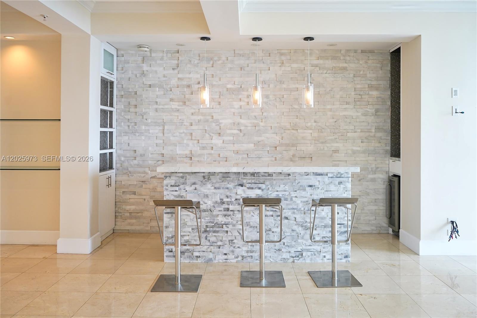 A home bar features a stone-tiled wall, a marble-topped counter, and three modern bar stools — 848 Brickell Key Dr # 306, Miami FL 33131, MIAMI, FL