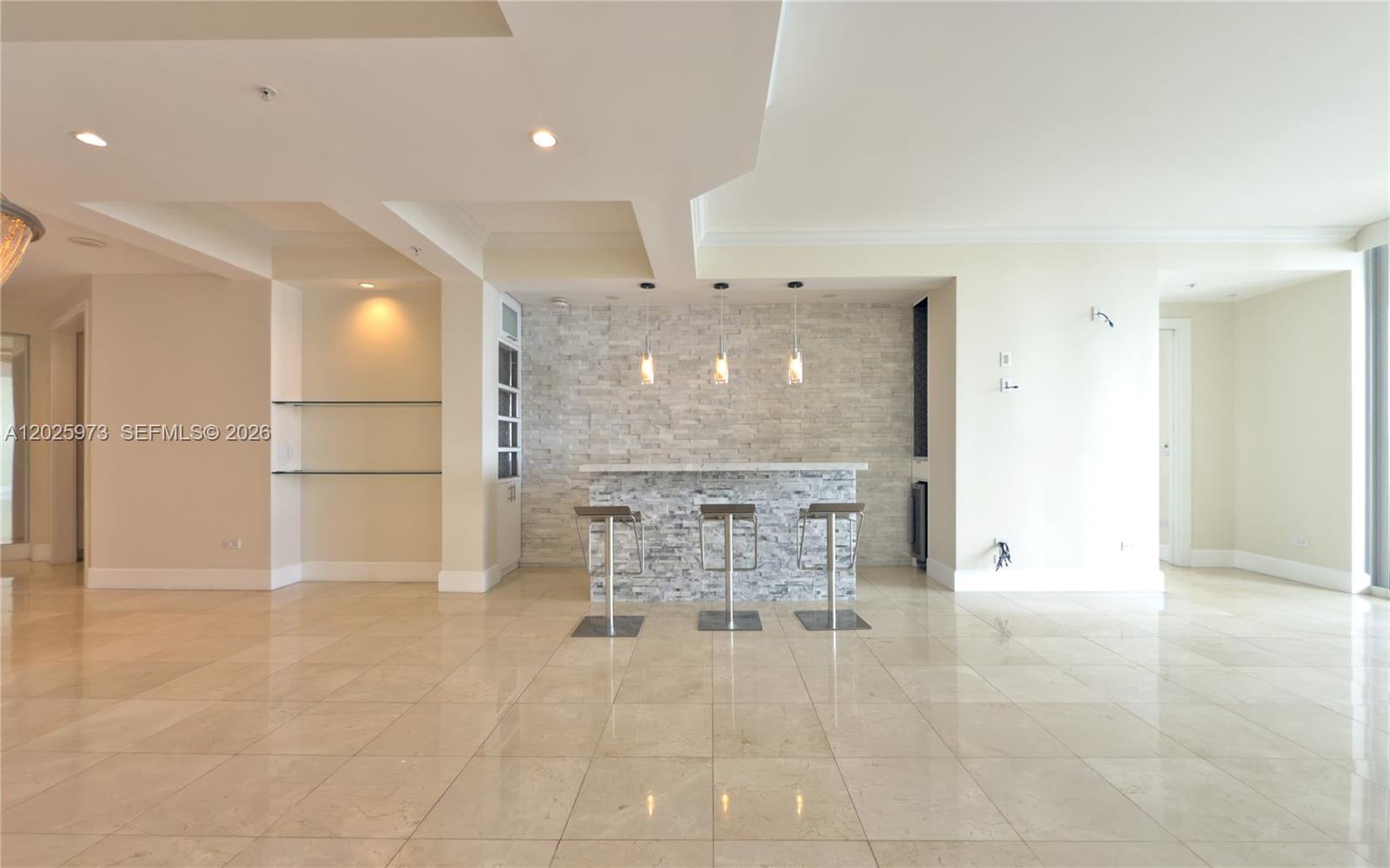A modern bar area features a stone-tiled wall, three stools, and recessed ceiling lighting — 848 Brickell Key Dr # 306, Miami FL 33131, MIAMI, FL