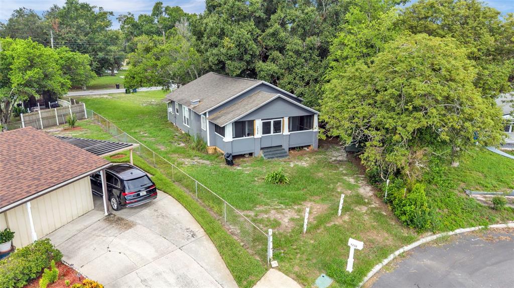 An elevated gray house with a screened front porch sits on a grassy corner lot — 1232 WRIGHT DRIVE, LAKELAND, FL
