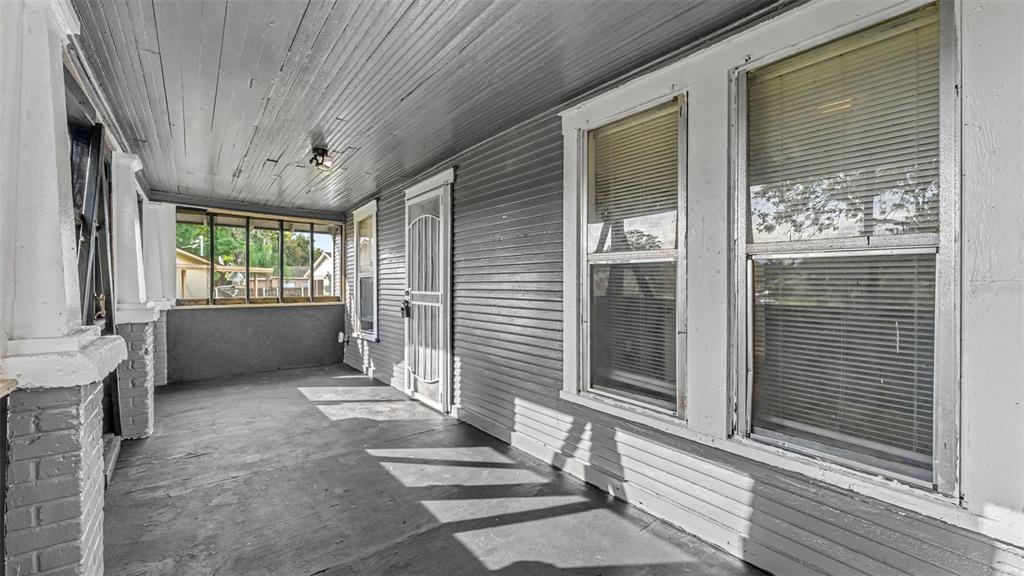A covered porch with gray painted wood siding, a concrete floor, and multiple windows — 1232 WRIGHT DRIVE, LAKELAND, FL