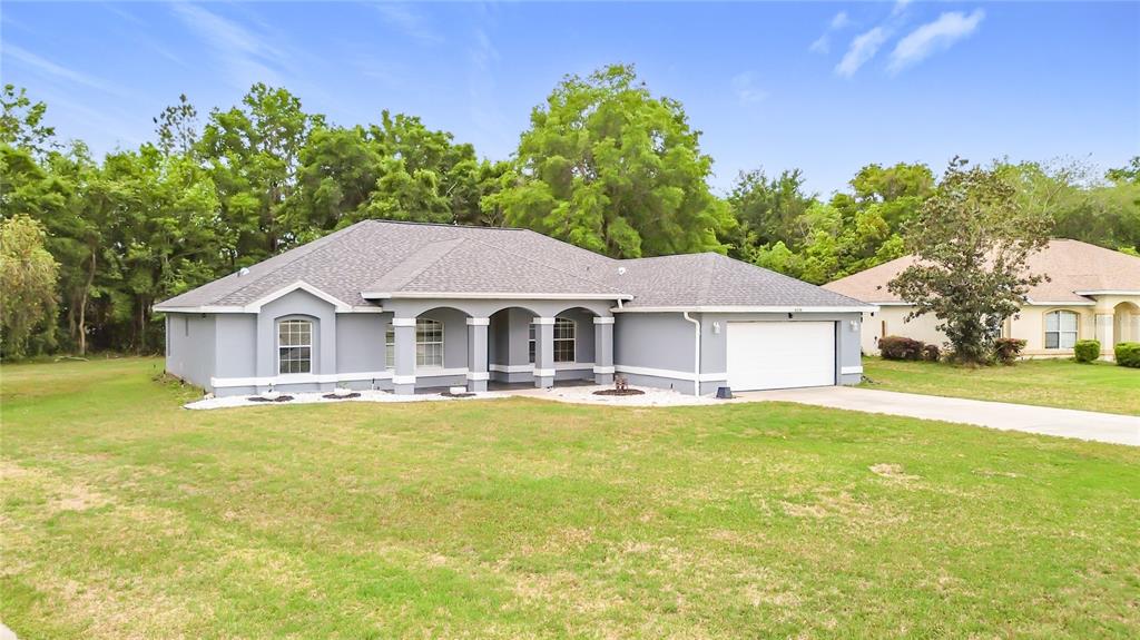 A gray, single-story house with a white garage and a covered front porch — 4319 NW 4TH CIRCLE, OCALA, FL