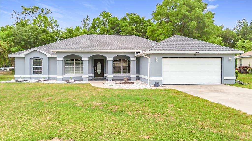 A single-story gray house with a white garage door, arched entryway, and a grassy lawn — 4319 NW 4TH CIRCLE, OCALA, FL